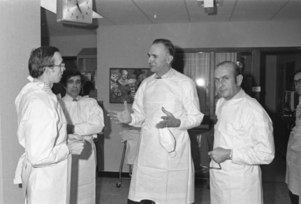 Four men in white lab coats having a lively conversation