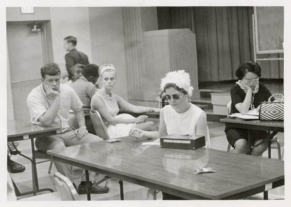 Students looking dejected and bored sitting at folding tables