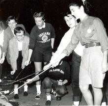 A group of students gathered around a fire, roasting marshmallows