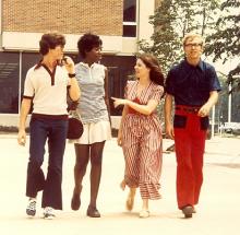 Three white students and a black student walking towards the camera talking