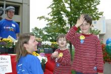 Two young boys in red and white striped shirts laughing with college students