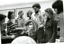 Seven students looking a teaching holding and bending three layers of foam stacked on top of each other