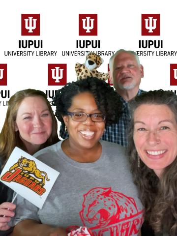 Members of the library administration suite holding IUPUI Jaguar memorabilia