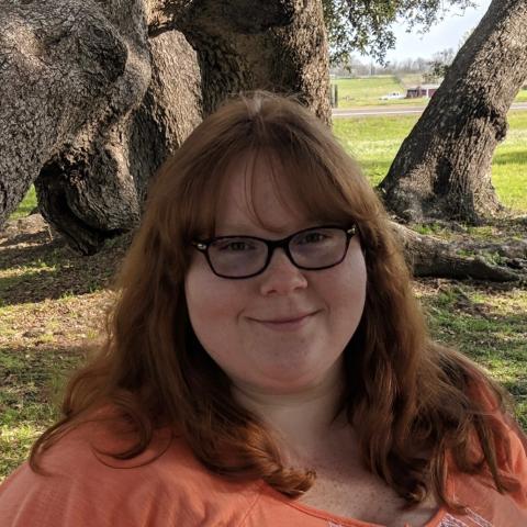 Photograph of Sam Bruer in front of a tree.