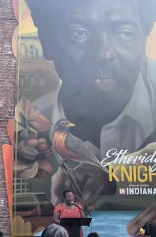 Ashley MAck-Jackson reciting a poem with the Etheridge Knight mural in the background