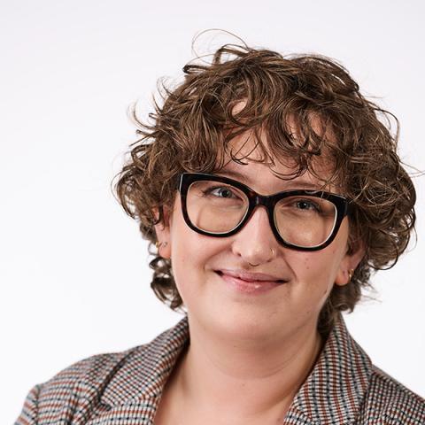 Woman with curly short hair and bold framed glasses