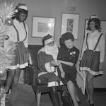 Woman sitting on Santa Claus while two female elves watch